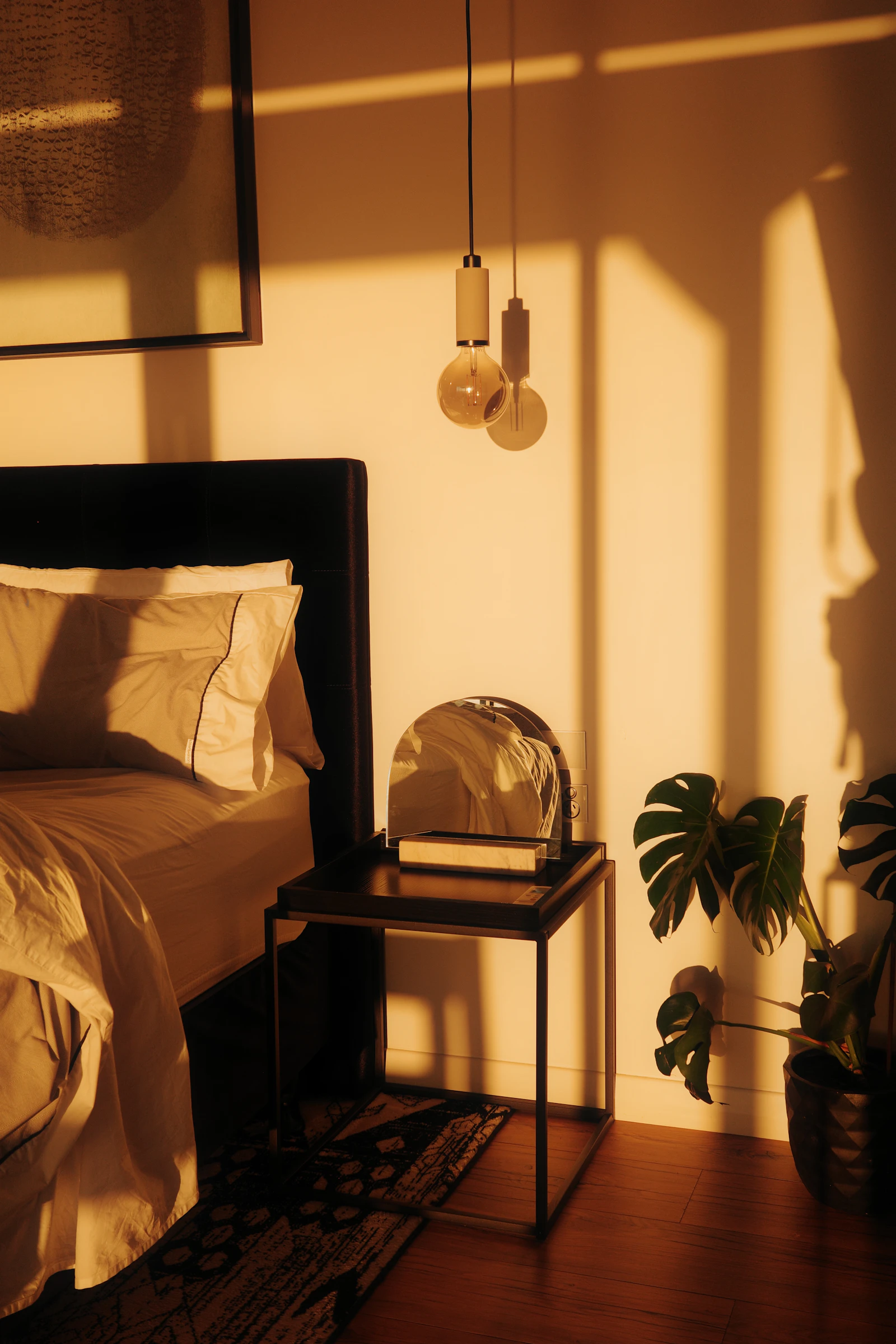 Warm light illuminating a bedroom with a bed and plant